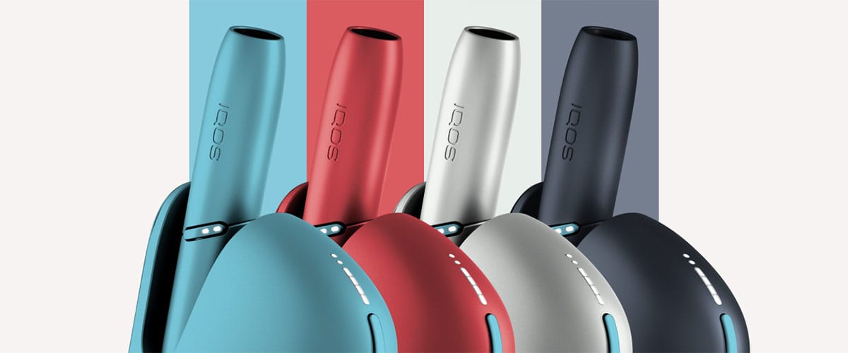 Person holding and using IQOS heated tobacco device outdoors